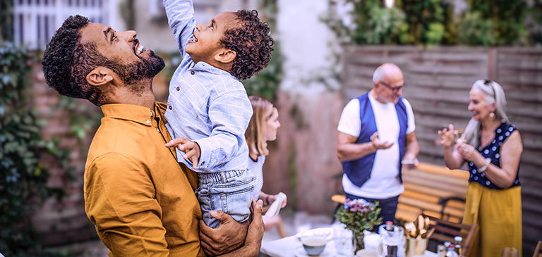 Father lifting child to fairy lights